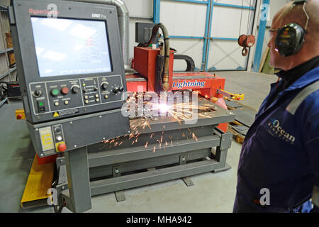 Mann bei der Arbeit auf einer metallenen Plasmaschneidemaschine in einer Werkstatt Stockfoto
