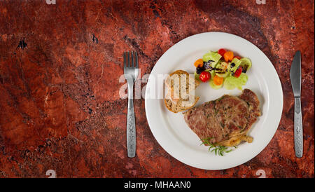 Reife, erfahrene Rind Rumpsteak oder Roastbeef Steak auf dem weißen Teller mit Salat und hausgemachtes Brot. Draufsicht auf Granit Hintergrund mit kopieren. Stockfoto