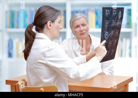 Frauen im mittleren Alter Arzt besprechen mit Ihrem älteren Schlaganfallpatienten ct-scan Bilder von ihr Gehirn Stockfoto