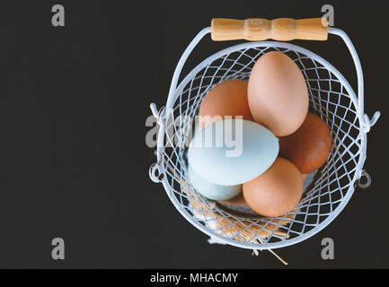 Blick von oben der Farm Fresh Käfig frei huhn eier. Landwirtschaft Ernte für Frühstück im Korb auf einem schwarzen Hintergrund Stockfoto