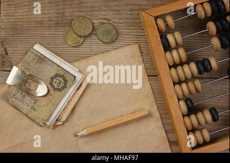 Alte Banknoten und Münzen und Abakus auf einem Holztisch Stockfoto