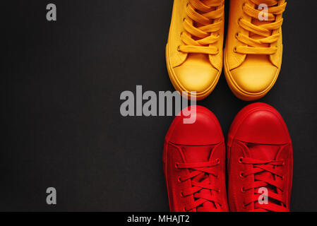 Junge erwachsene Menschen auf eine liebe Datum, konzeptionelle Bild. Blick von oben auf die zwei Paar lässige Sneakers, Gelb und Rot, von oben Stockfoto