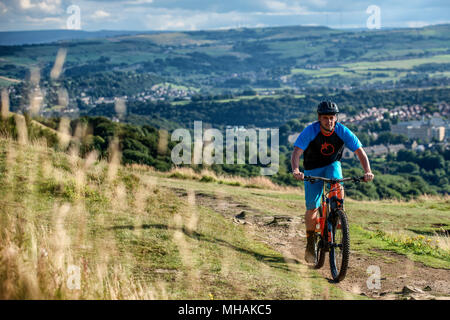 Ein Mann reitet einen elektrischen Pedal e-Bike in der Nähe der Stadt Halifax im Norden von England zu unterstützen. Stockfoto