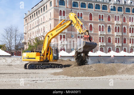 Bagger (Bagger) bewegten Sand am Strand des Lido di Venezia, Venedig, Venetien, Italien vor der Excelsior Hotel vorbereiten für den Sommer se Stockfoto