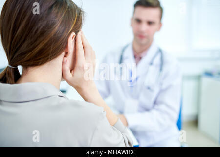 Zurück Porträt der jungen Frau leidet unter Kopfschmerzen sprechen in Klinik Arzt anzeigen, kopieren Raum Stockfoto