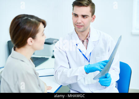 Portrait von hübscher junger Arzt Holding x-ray erklärt sich bei weiblichen Patienten, Kopie Raum Stockfoto