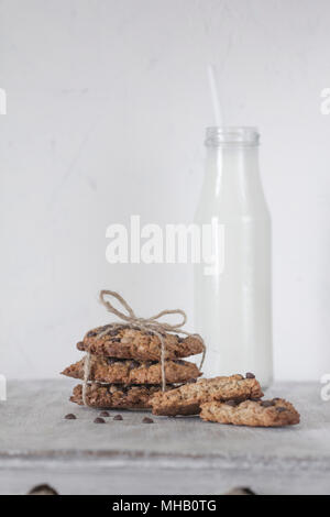 Der frisch gebackene Hausgemachte oatmeal Cookies mit Tropfen von brauner und weißer Schokolade mit Milch. Anzeigen in einem Winkel. Close-up. Stockfoto