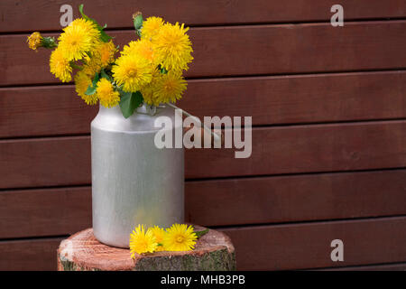 Löwenzahn in einer Vase auf einem hölzernen Hintergrund. Immer noch leben. Stockfoto