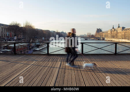 Verschwommene Bewegung Bild von zwei Männern Spaziergang mit einem Hund auf Pont des Arts Brücke über die Seine in Paris. Stockfoto