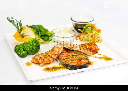 Steaks von Lachs, gegrillt. Mit Gemüse und Gewürze auf dem weißen Teller serviert Stockfoto