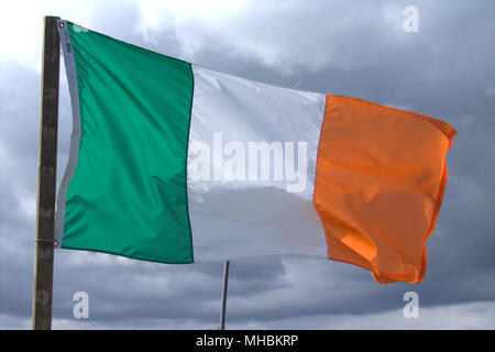 Irland Nationalflagge Tricolour und Stern der Republik Irland fliegen in einem steifen Wind gegen einen stürmischen Himmel. Stockfoto