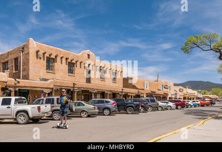 Mann, der auf einem selbstbalancierenden Segway, Hoverboard und Scooter fährt, während er auf einer Straße im historischen Taos Plaza, Taos, New Mexico, USA, mit Bällen jongliert. Stockfoto