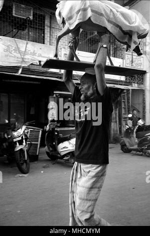 Ein Mann, der die Statue einer Kuh auf den Kopf durch einen Market Street, Mumbai, Indien Stockfoto