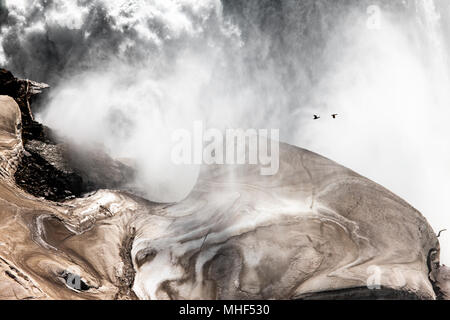 Farbe Landschaftsfotografie, Wasser aus dem American Falls, Niagara Falls, USA schlagen und Gestaltung Eis und Schnee auf den Felsen unten. Stockfoto