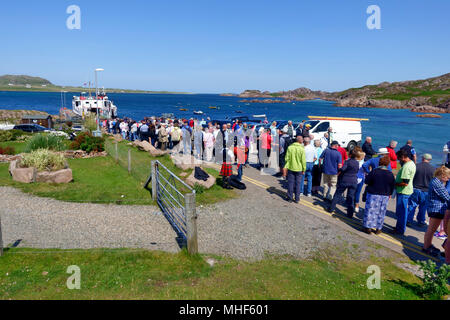 Touristen Queuing in Fionnphort, Mull für die Fähre nach Iona und wird von einem jungen Piper unterhalten Stockfoto