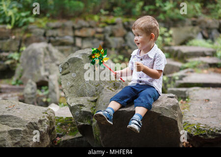 Little Boy spielen im Park mit windmühle Windrad. Im freien Freizeit Freundschaft Familie Konzept. Stockfoto