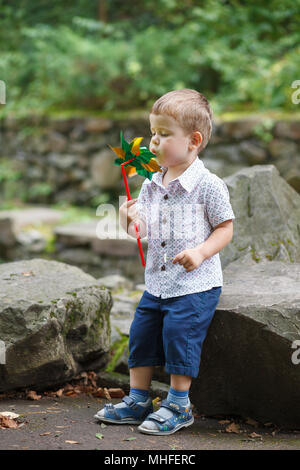 Little Boy spielen im Park mit windmühle Windrad. Im freien Freizeit Freundschaft Familie Konzept. Stockfoto