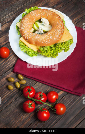 Vollkornbrot Bagel mit grünem Pesto, frisches Gemüse, Käse, Tomaten und Birne. Stockfoto