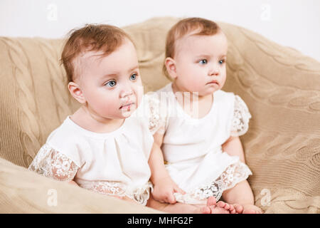 Zwei adorable Baby Zwillinge im Stuhl sitzen. Stockfoto