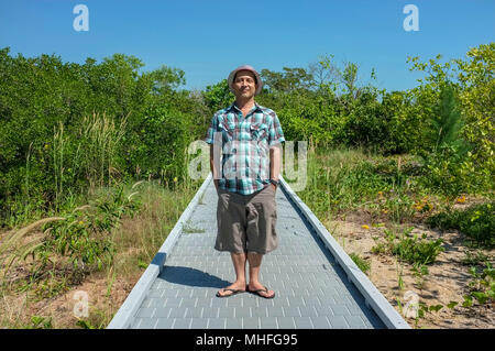 Mann mit den Händen in seiner Tasche aufstehen und in die Kamera auf der East Point Reserve Mangrove Boardwalk in Darwin, Australien. Stockfoto