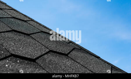 Die Textur der Dachziegel Schindeln mit einem blauen Himmel im Hintergrund. Baumaterial. Perspektive betrachten. Nahaufnahme Stockfoto