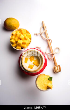 Mango Lassi oder Smoothie in großen Glas oder kleine Flaschen mit Quark, Obst Stücke schneiden und Mixer. Moody Hintergrund, selektiver Fokus Stockfoto