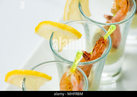 Einzelne Cocktail Shrimps Shot Gläser mit köstlichen hausgemachten Zahnstein pikanter Sauce mit Petersilie Blatt für das Weihnachtsessen oder cocktailparty eingerichtet, bokeh Hintergrund, Nahaufnahme Stockfoto