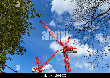 Eigenschaft Entwicklung: Zwei grossen roten Turmdrehkrane vor blauem Himmel auf einer Baustelle im Zentrum von London, Großbritannien Stockfoto