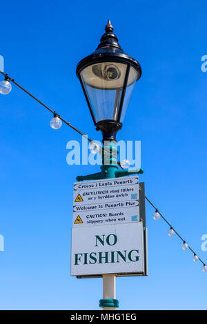 Keine Fischerei auf einem lampost auf Penarth Pier, auch mehrsprachig Zeichen in Walisisch und Englisch warnen vor Rutschigen Bretter, Tal von Glamorgan, Wales, Großbritannien Stockfoto