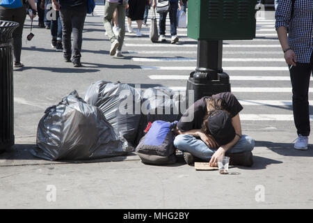 Obdachloser gefaltet auf dem Bürgersteig mit Abfallbeutel für Pick-up entlang der Straße in Manhattan, New York City. Stockfoto