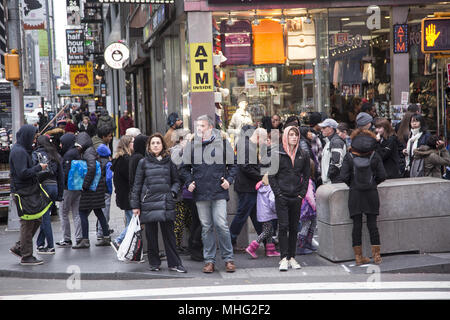 Vor allem Touristen mit Tüten warten 42. Straße zu überqueren in der Times Square Gegend in Midtown Manhattan, NEW YORK CITY. An einem kühlen Frühlingstag. Stockfoto