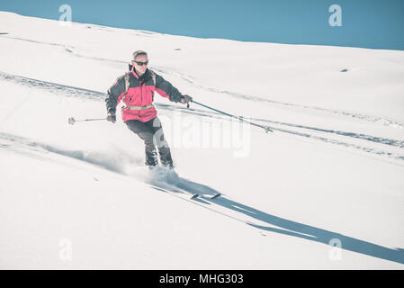 Man Skifahren off piste auf schneebedeckten Hang in den italienischen Alpen, mit hellen, sonnigen Tag der Wintersaison. Pulverschnee mit Skipisten. Getonten Bild Stockfoto