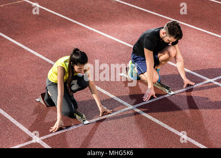 Männliche und weibliche Athleten in der Ausgangsposition an der Startblock Stockfoto