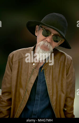 Porträt älterer asiatischer Mann isoliert vor einem schlichten Hintergrund Stockfoto