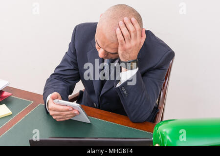 Der Mann am Schreibtisch, betrachten Sie Ihre i Pad/Tablet, in seinem Büro. Stockfoto