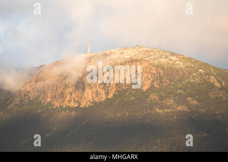 Erstes Licht an einem bewölkten, Schnee bestäubt Mount Wellington über Hobart Stockfoto