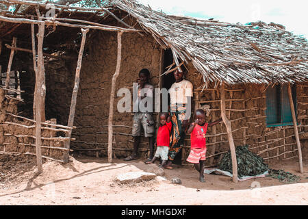 Eine arme afrikanische Familie besteht aus drei Kinder und ihre Mutter, die von Ihrer Hütte aus Kot und Zement an den Grenzen der Savanne Stockfoto