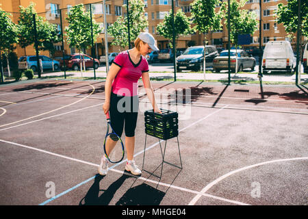 Frau, Tennis Spieler, Bälle in einen Korb auf dem Tennisplatz. Stockfoto