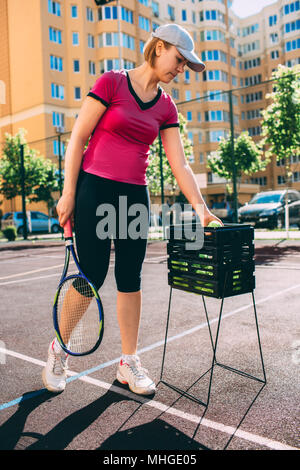 Frau, Tennis Spieler, Bälle in einen Korb auf dem Tennisplatz. Stockfoto