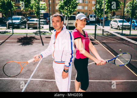 Zwei lächelnde Tennisspieler holding Tennisschläger, vor dem Beginn des Set, stehend auf dem städtischen Tennisplatz Stockfoto