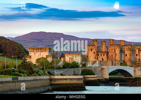 Einen schönen Sonnenaufgang Sonnenaufgang und Einstellung Mond über Conwy Castle und Carnedd Llewelyn und dem Beginn des Snowdonia National Park, Cowny, Wales, Großbritannien Stockfoto