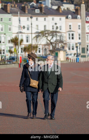 Ältere Paare der Mann und die Frau zu Fuß Seite an Seite entlang der Uferpromenade in Llandudno in North Wales auf einem sonnigen Morgen im Ruhestand, Großbritannien Stockfoto