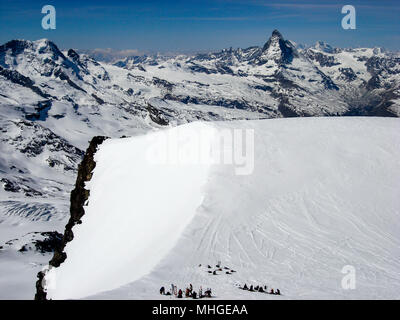 Viele Langläufer auf hohem Gipfelplateau in den Schweizer Alpen in der Nähe von Zermatt mit einem tollen Blick auf das Matterhorn hinter Ihnen Stockfoto