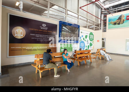 Passagiere warten auf Bänken in der Seymour Flughafen auf der Insel Baltra, Galapagos, Ecuador. Der Flughafen ist LEED Gold zertifiziert. Stockfoto