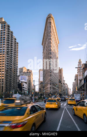 NEW YORK CITY - 4. SEPTEMBER 2016: Gelbe Taxis Pass vor dem Flatiron Building, einer der ersten und berühmtesten Wolkenkratzer der Stadt. Stockfoto