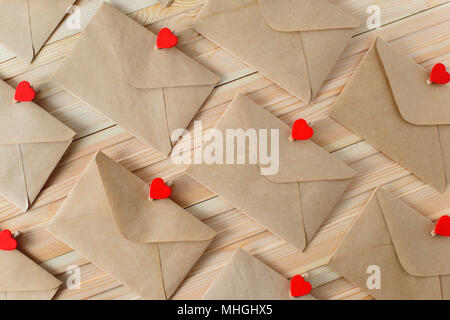 Umschläge aus dem craft-Papier mit roten Herzen Pins auf dem Holz- Hintergrund. Stockfoto