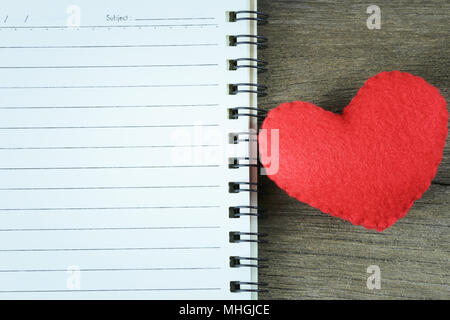 Rotes Herz und ein leeres Notebook auf einem Holzboden und kopieren, um Platz zu Eingang Idee in ihrer Arbeit. Stockfoto