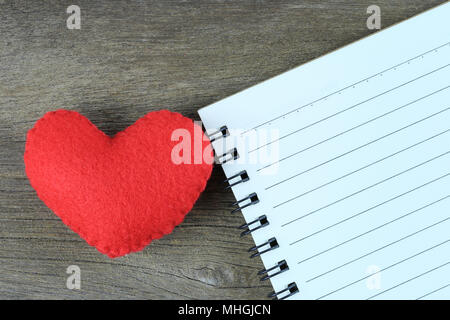 Rotes Herz und ein leeres Notebook auf einem Holzboden und kopieren, um Platz zu Eingang Idee in ihrer Arbeit. Stockfoto