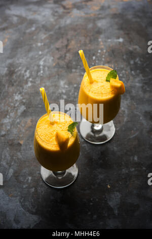 Mango Lassi oder Smoothie in grosses Glas mit mint Blatt. Flankendehnung über bunten Hintergrund isoliert. Selektiver Fokus Stockfoto