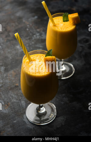 Mango Lassi oder Smoothie in grosses Glas mit mint Blatt. Flankendehnung über bunten Hintergrund isoliert. Selektiver Fokus Stockfoto